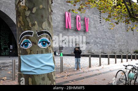 Covid-19 Pandemie Melbourne Australien 2020. Chirurgische Gesichtsmaske auf einem Baum vor der National Gallery of Victoria in Melbourne. Stockfoto