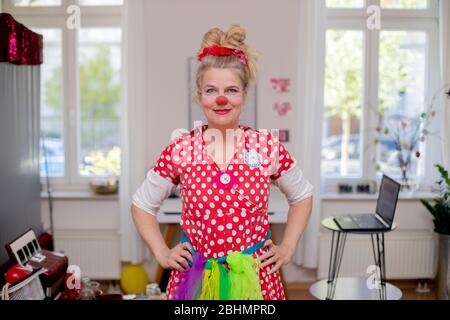 14. April 2020, Brandenburg, Potsdam: Ute von Koerber, Klinikclown "Vitamine" des Potsdamer Vereins "Lachen hilft", steht vor einer virtuellen Clownberatung in ihrer Wohnung. Als Klinikclown erlebt sie Menschen in Krankenhäusern, Pflegeeinrichtungen und medizinischen Einrichtungen direkt in ihrem Zimmer in ihrer Situation. All das fehlt jetzt und die Menschen müssen virtuell erlebt werden, sagt der 54-Jährige. Durch die virtuelle Clown Sprechstunde können Kinder direkt am Bett besucht werden. Sie ist dankbar, dass es so funktioniert, aber direkter Kontakt kann nicht sein Stockfoto