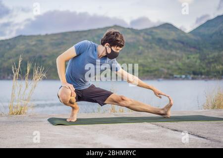 Junger Mann in medizinischer Maske Durchführung einiger Workouts im Park während Coronavirus Quarantäne, Coronavirus Pandemie Covid-19. Sport, Aktives Leben in Stockfoto