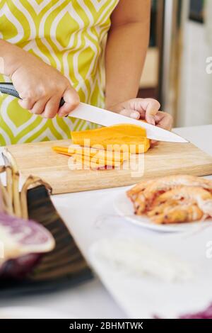 Hausfrau Schneiden Karotte in dünne Scheiben mit scharfen Messer beim Kochen Abendessen Stockfoto