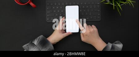 Overhead-Aufnahme von Unternehmerin mit leerem Bildschirm Smartphone zu entspannen, während die Arbeit mit digitalen Gerät auf schwarzem Tisch Stockfoto