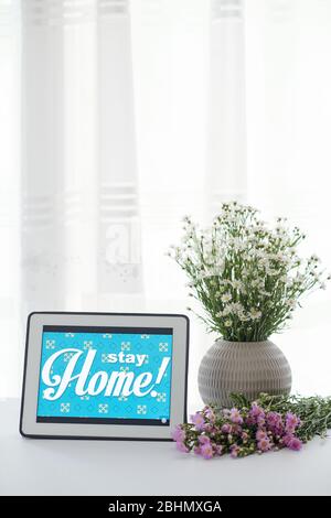 Bleiben Sie zu Hause Beratung auf Tablet-Computer und Vase mit blühenden Wildblumen Stockfoto