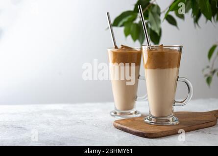 Zwei Dalgona Kaffee in hohen Gläsern auf weißem Hintergrund. Platz für Text Stockfoto