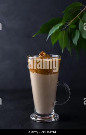 Dalgon Kaffee in einer Glasbecher auf schwarzem Hintergrund. Koreanisches Getränk mit Milch und Schlagkaffee Stockfoto