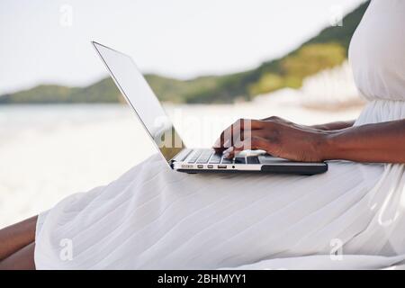 Freiberufliche Frau sitzt am Strand der tropischen Insel und arbeitet am Laptop Stockfoto