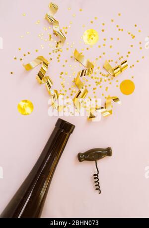 Goldene Streamer, Pailletten, goldene Spiralen und Sterne explodieren und fliegen wie ein Feuerwerk aus dem Hals einer Flasche dunkles Glas, ein Weinöffner im Beig Stockfoto