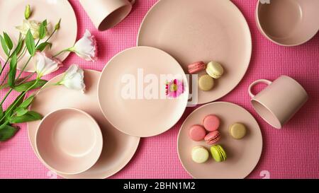 Draufsicht auf modernes, in Pastellrosa gefertigter Keramikgeschirr auf rosafarbenem Boden. Kreatives Konzept Kochen, Küche Flatlay Layout. Kreative Beleuchtung. Stockfoto