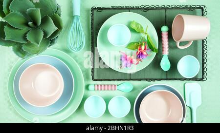 Draufsicht auf modernes, in Pastellrosa, grün und blau gedeckter Keramikgeschirr in hellgrün. Kreatives Konzept Kochen, Küche Flatlay Layout. Stockfoto