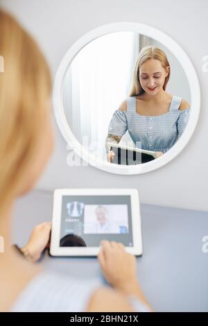 Lächelnd hübsche junge Frau Video ruft ihren Arzt, um ihre medizinischen Tests und Rezept zu diskutieren Stockfoto