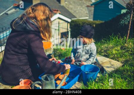 Eine junge Mutter und ihr Vorschulalter Pflanzen an einem Frühlingstag Samen im Garten Stockfoto