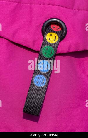 Bunte lächelnde Emoticons auf einem Stoffband. Schwarzes Band auf rotem Hintergrund. Vertikal. Stockfoto