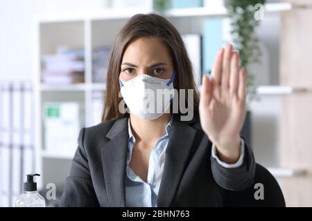 Vorderansicht der Exekutive, die eine Schutzmaske trägt und eine Stoppbewegung im Büro macht Stockfoto