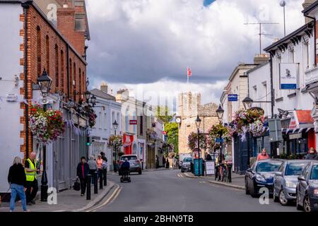 Hauptstraße mit vielen Geschäften und Pubs in Dalkey, Irland. Fußgänger, die einkaufen und Autos parkten und entlang der Straße gefahren. Stockfoto