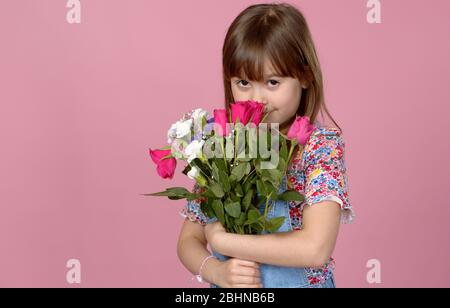 Süße liebenswert junge Mädchen hält Bündel von frischen Frühlingsblumen. Tragen Latzhose Stockfoto