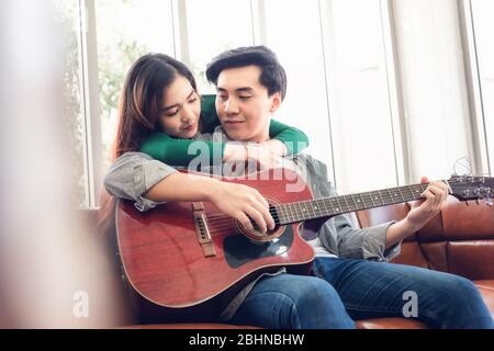 Junges Paar Liebe Spaß haben während Sing ein Lied und Gitarre spielen in Wohnzimmer zusammen, Portrait von Paar sind zu Hause entspannen. Romantisches Lif Stockfoto