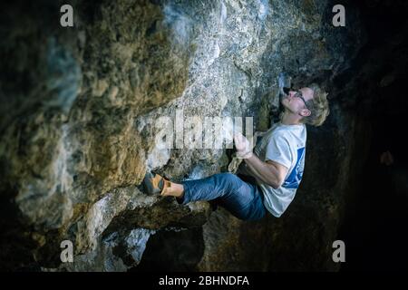 Der Mensch macht einen Felsbrocken in der Twardowski Höhle. Bouldern im Fels. Twardowski Höhle Stockfoto