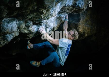 Der Mensch macht einen Felsbrocken in der Twardowski Höhle. Bouldern im Fels. Twardowski Höhle Stockfoto