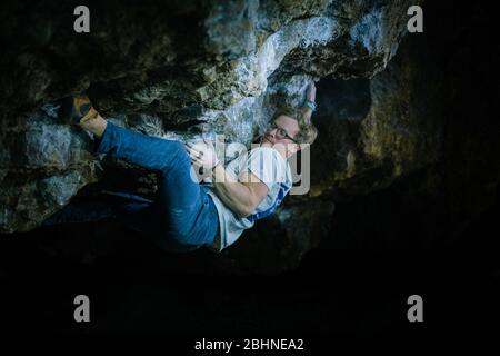 Der Mensch macht einen Felsbrocken in der Twardowski Höhle. Bouldern im Fels. Twardowski Höhle Stockfoto