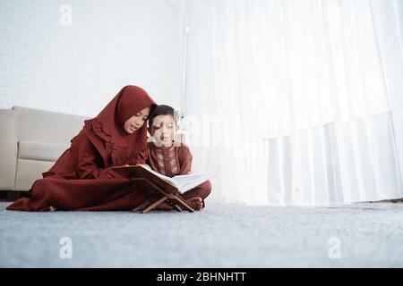 Der asiatische Junge lernt mit seiner Schwester zu Hause den Al-Quran Stockfoto