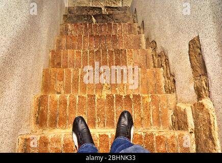 In schwarzen Schuhen auf einer alten Steintreppe stehend. Stockfoto