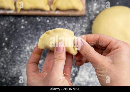 Knödel in Mehl auf dem Holzbrett, die Hände sind varenik vor dem Kochen gemeißelt. Draufsicht, Nahaufnahme Stockfoto