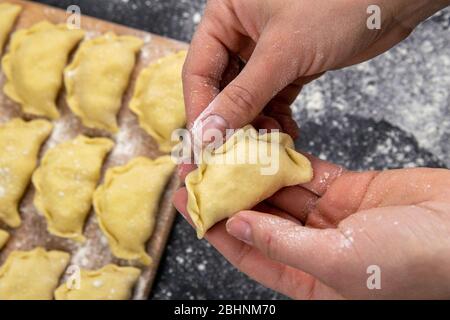 Knödel in Mehl auf dem Holzbrett, die Hände sind varenik vor dem Kochen gemeißelt. Draufsicht, Nahaufnahme Stockfoto