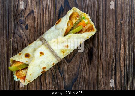 Döner wickeln Kebab. Shawarma mit Fleisch, Zwiebeln, Salat liegt auf einem dunklen alten Holztisch. Von oben mit viel Platz Stockfoto