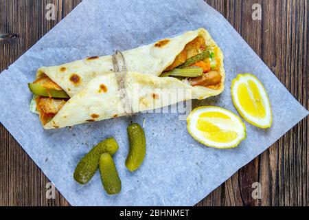 Köstlicher türkischer Döner Kebab auf Pita-Brot mit rasierten gebratenem Fleisch aus einer traditionellen vertikalen Rotisserie, serviert mit frischen Salatzutaten Stockfoto