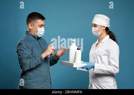 Arzt Anwendung antibakteriellen Spray auf Patienten Hände auf blauem Hintergrund Stockfoto