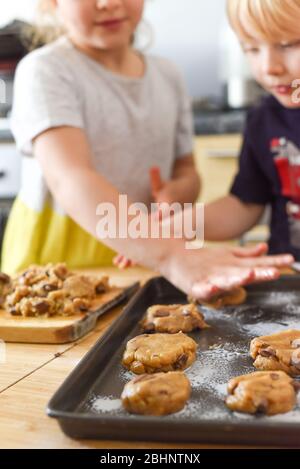 Kinder machen Kekse in der Küche, indem sie Teig auf ein Tablett zum Kochen zu Hause legen Stockfoto