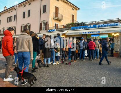 Viele Leute stehen in der Schlange und warten darauf, Eis vor einem Eisgeschäft in der Altstadt von Bardolino, Gardasee, Verona, Venetien, Italien zu kaufen Stockfoto