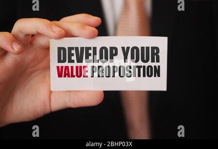 Geschäftsmann zeigt eine Karte mit Text ENTWICKELN SIE IHRE VALUE PROPOSITION. Management Business Leistungen Motivation Konzept Stockfoto