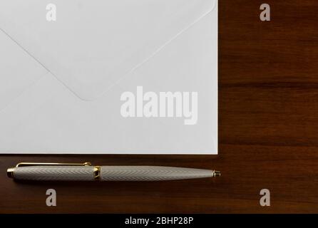 Elagant Stift neben einem weißen Umschlag auf einem Holztisch Stockfoto