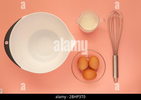 Schneebesen und eine Plastikbecher zum Schlagsacken auf einem rosa Hintergrund. Stockfoto