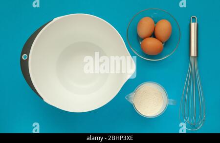 Schneebesen und eine Plastikbecher zum Schlagsacken auf blauem Hintergrund. Stockfoto