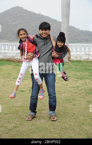 Nathdwara, Rajasthan, Indien, Asien - 23. Januar 2014 - Indischer Familienvater mit zwei kleinen niedlichen Mädchen spielen im Park Stockfoto