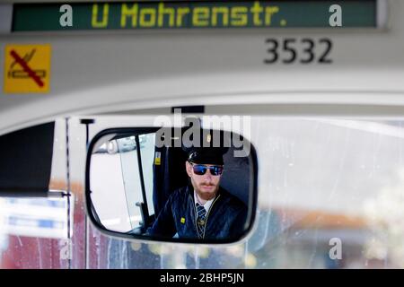 06. April 2020, Berlin: Marcel Kohlschmidt, Busfahrer, ist im Innenspiegel seines Busses zu sehen. Es gebe weniger Verkehr auf den Straßen, weniger Passagiere und gelegentlich eine gruselige Stille, sagt der 28-Jährige. Der Vordereingang ist blockiert, eine Folie schützt den Fahrer vollständig vor dem Passagierbereich und Fahrkarten werden nicht mehr im Bus verkauft. Er glaubt bereits, dass einige Leute nutzen diese, um schwarz zu fahren, vor allem, da die Ticketeinnahmen um 95 Prozent gesunken sind. Wird ein Rollstuhlfahrer in den Bus eingeladen, schützt er sich mit Maske und Handschuhen. Kohlschmidt ist weniger schierlos Stockfoto