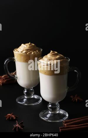 Dalgona cremiger Kaffee in zwei Gläsern auf schwarzem Hintergrund mit Schlagschaum. Koreanischer Kaffee Trend, Vertikal-Format Stockfoto