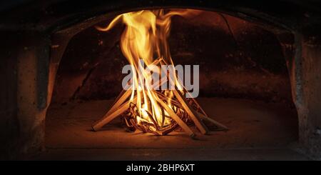 Das Feuer in einem traditionellen Holzofen für die Zubereitung der neapolitanischen Pizza zu entzünden. Stockfoto