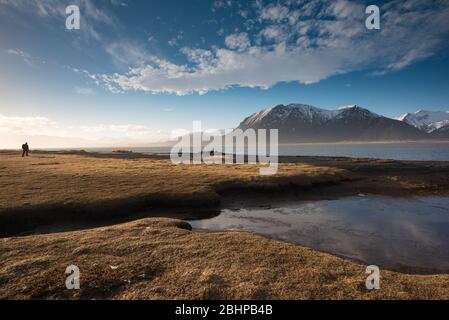 Eine Einzelfigur an der Lagune auf der schwarzen Sandspieß in Eystrahorn, Island Stockfoto