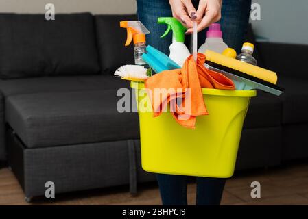 Ein Mädchen hält Waschmittel in einem Eimer auf dem Hintergrund. Frau ist bereit, Haus zu reinigen. Reinigung in einem Haus. Haus reinigen und waschen. Eine Hausfrau ist Hausfrau. Stockfoto