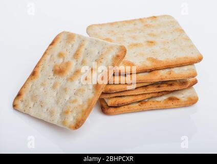 Stapel von quadratischen organischen knusprigen und salzigen Cracker auf weißem Hintergrund. Stockfoto
