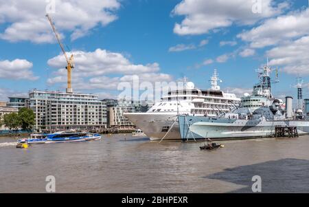 Verkehr auf dem Londoner Fluss. Eine geschäftige Themse mit dem Kreuzfahrtschiff Silver Wind liegt neben der HMS Belfast, während ein Flussbus vorbeifährt. Stockfoto