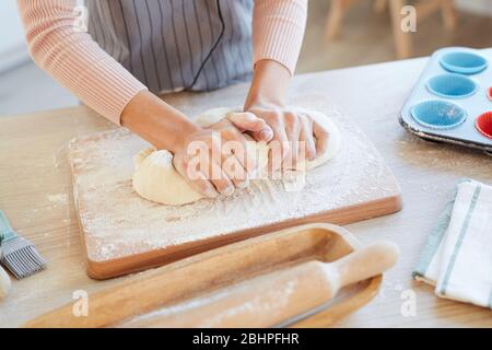 Hoch Winkel horizontale Schuss von weiblichen Händen Kneten Backteig auf Holz Küchenbrett für Cupcakes Stockfoto