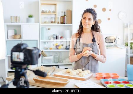 Attraktiver Food Vlogger bereitet Teig für das Backen während der Videoaufnahme auf der Kamera vor Stockfoto