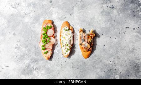 Verschiedene italienische Vorspeise Bruschetta oder Tapas-Set mit verschiedenen herzhaften und süßen Belag auf grauen Beton background.Top view, kopieren Raum Stockfoto