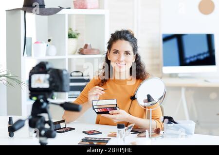 Horizontales Porträt einer jungen Frau, die Lippenstift hält und Video für ihren Beauty-Blog-Kanal aufzeichnet Stockfoto