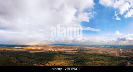 Luftlandschaft. Wald und Stadt am Horizont Panoramablick an bewölkten Tagen mit entfernten Regenfällen Stockfoto