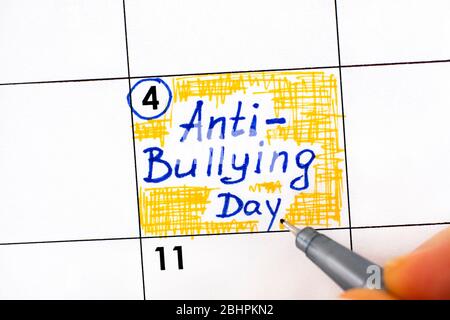 Frau Hand mit Stift Schreiberinnerung Anty - Mobbing Day im Kalender. Mai 04. Stockfoto