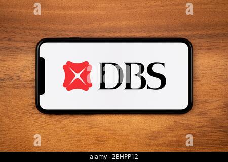 Ein Smartphone mit dem Logo der DBS Bank liegt auf einem einfachen Holztisch (nur für redaktionelle Zwecke). Stockfoto